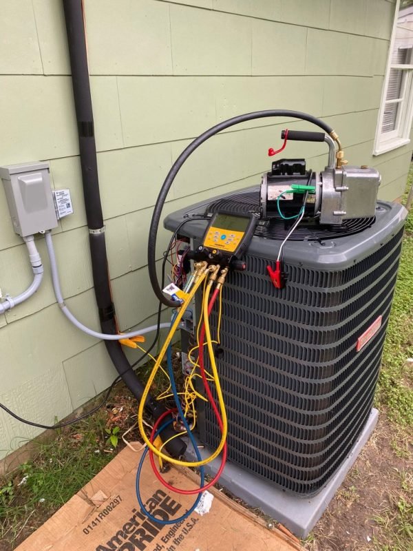 Air conditioner condenser being serviced with digital manifold gauges and vacuum pump
