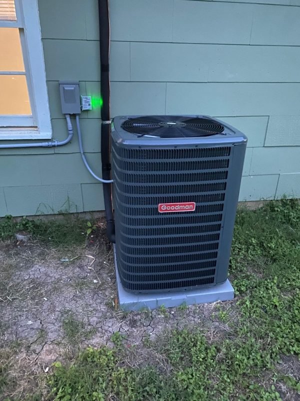 New Goodman air conditioning condenser installed beside a home