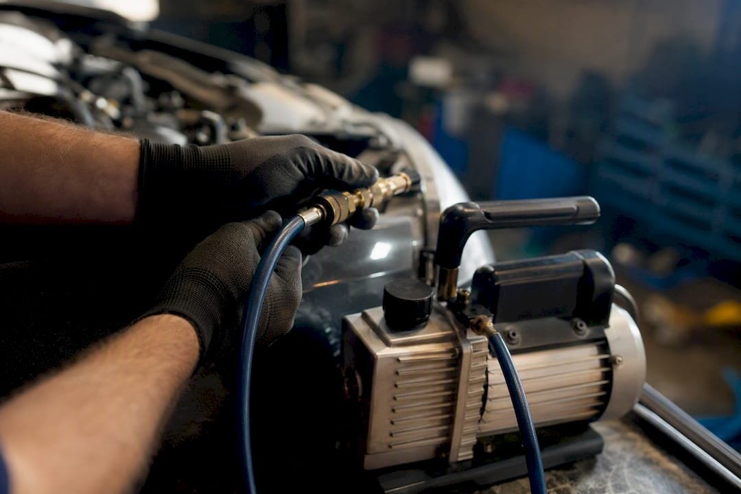 Technician evacuating automotive A/C system with vacuum pump