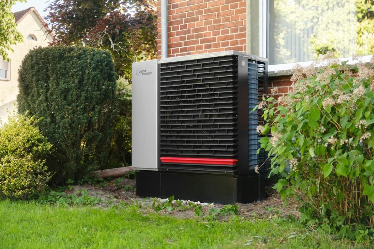 Outdoor heat pump condenser beside a brick house