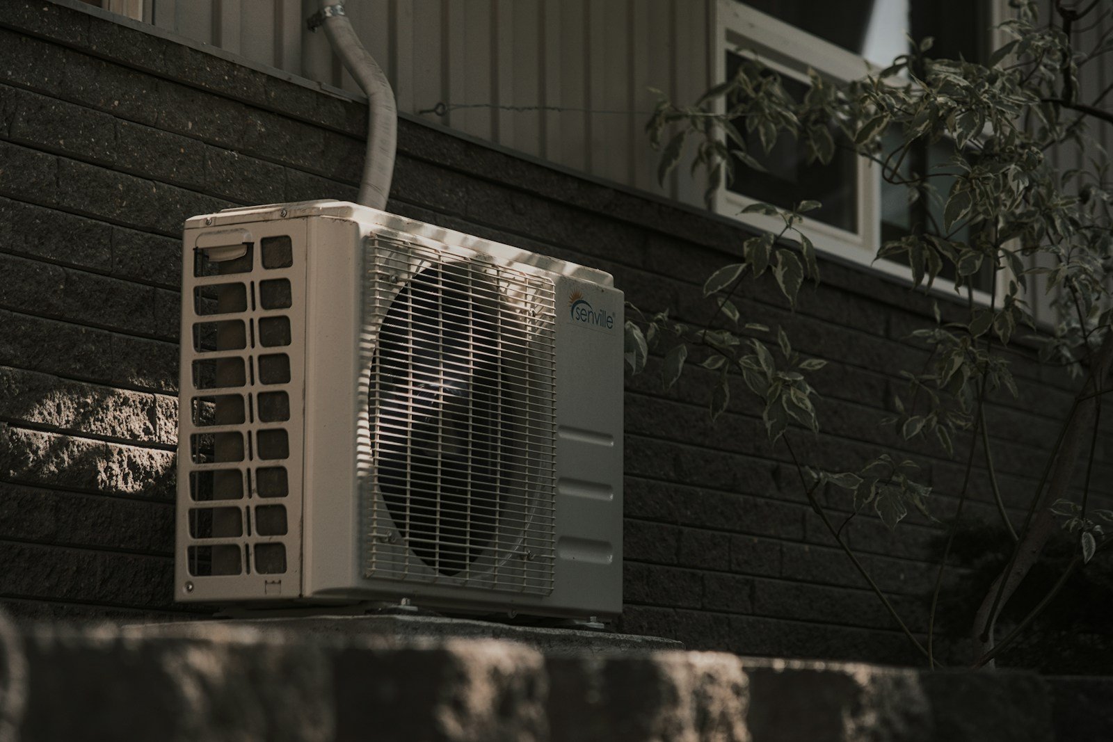 Residential air conditioner condenser on a brick wall