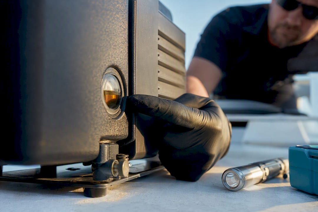 Technician checking vacuum pump oil sight glass